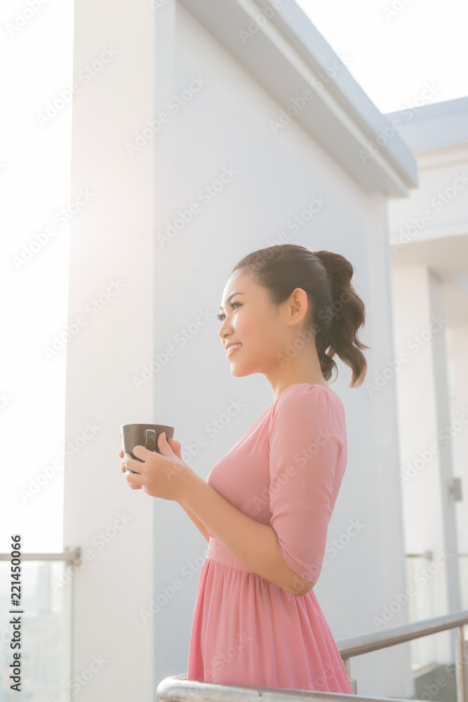 年轻女子拿着咖啡杯微笑着看着镜头