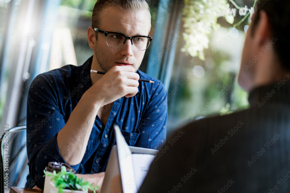 两个聪明的白人男子在窗户咖啡馆附近会面并进行严肃而专注的交谈