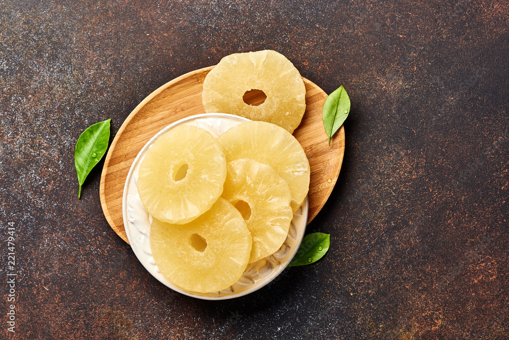 Dried pineapple rings on a brown table. Top viw of sweet paneapple slices.