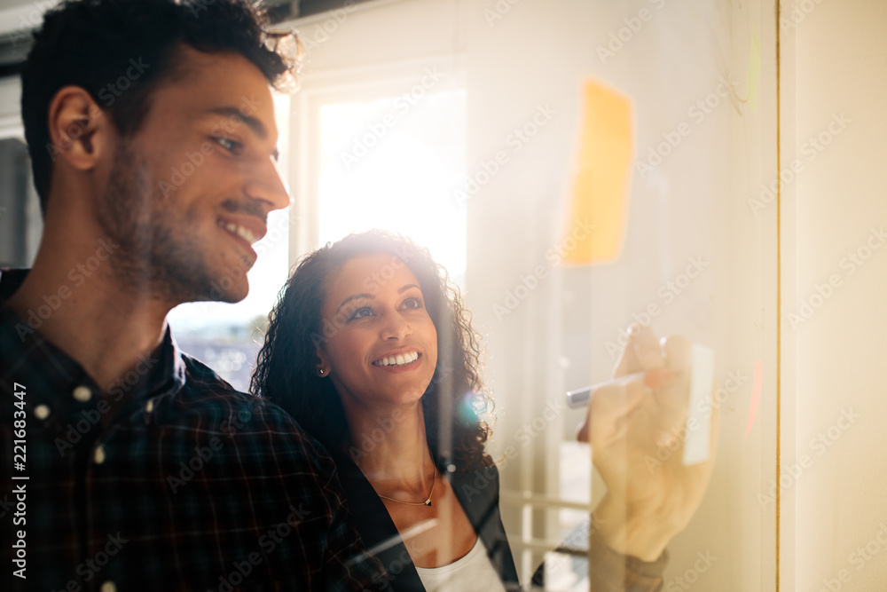 Business colleagues discussing ideas on glass board in office