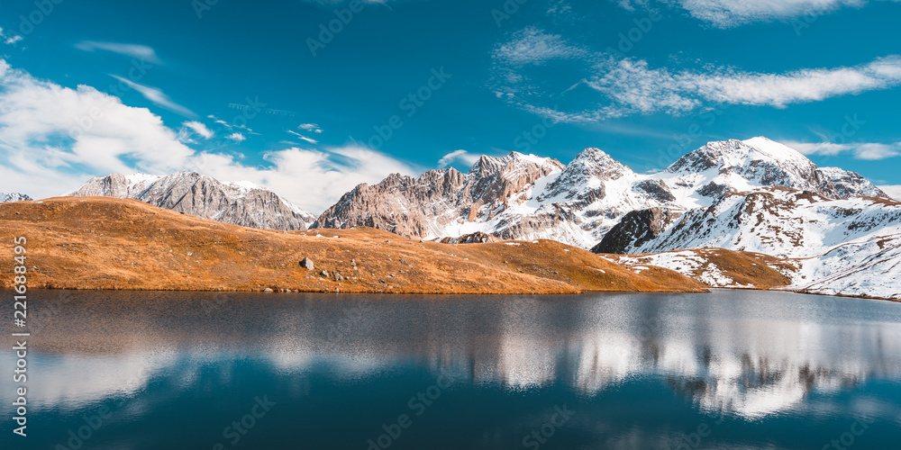 Colorful sunlight behind majestic mountain peaks of the Italian - French Alps, viewed from distant. 