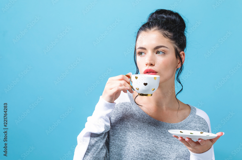 Young woman drinking coffee on a solid background