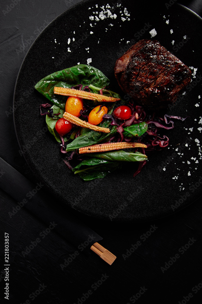 Teriyaki酱多汁牛肉与烤樱桃番茄、红甘蓝和树叶的特写