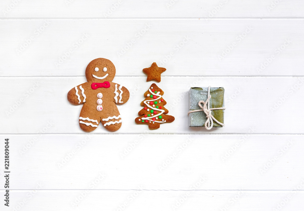 Сreative Christmas composition with cookie gingerbread men, Christmas tree and gift on white wooden 