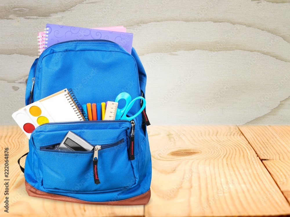 School Backpack with stationery on wooden table