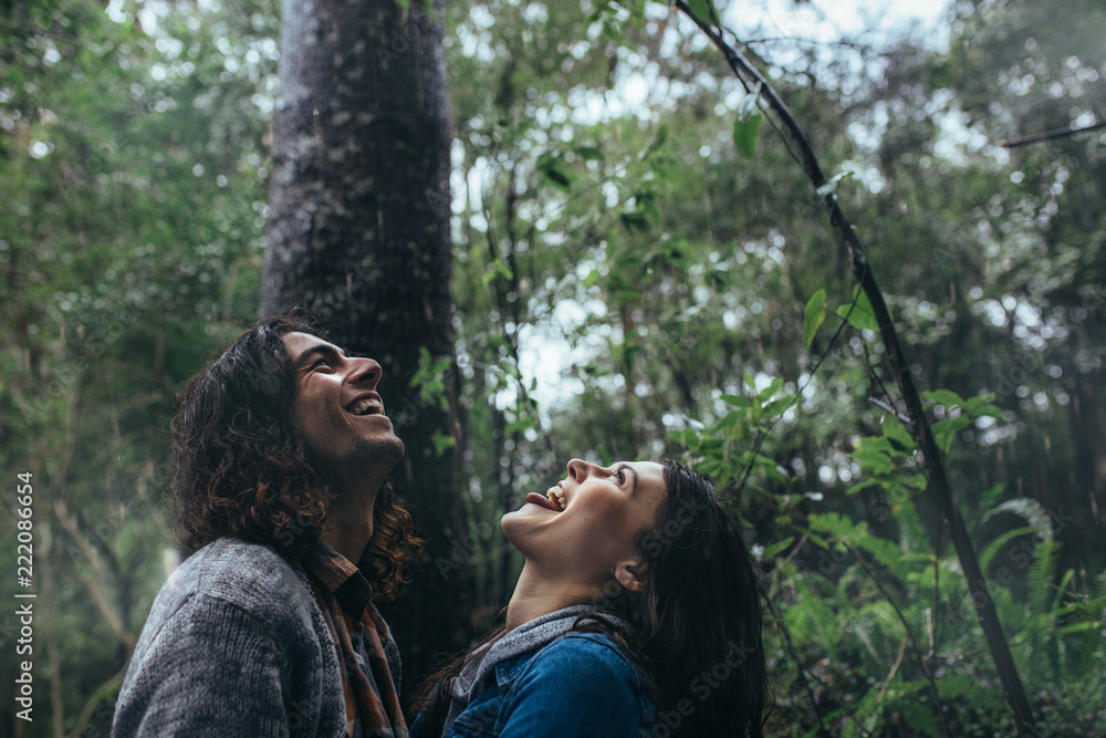 Couple catching raindrops on tongue in rainforest