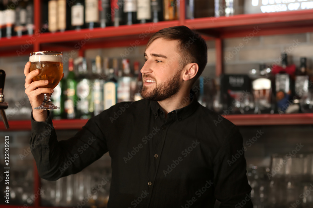 Bartender with glass of beer in bar