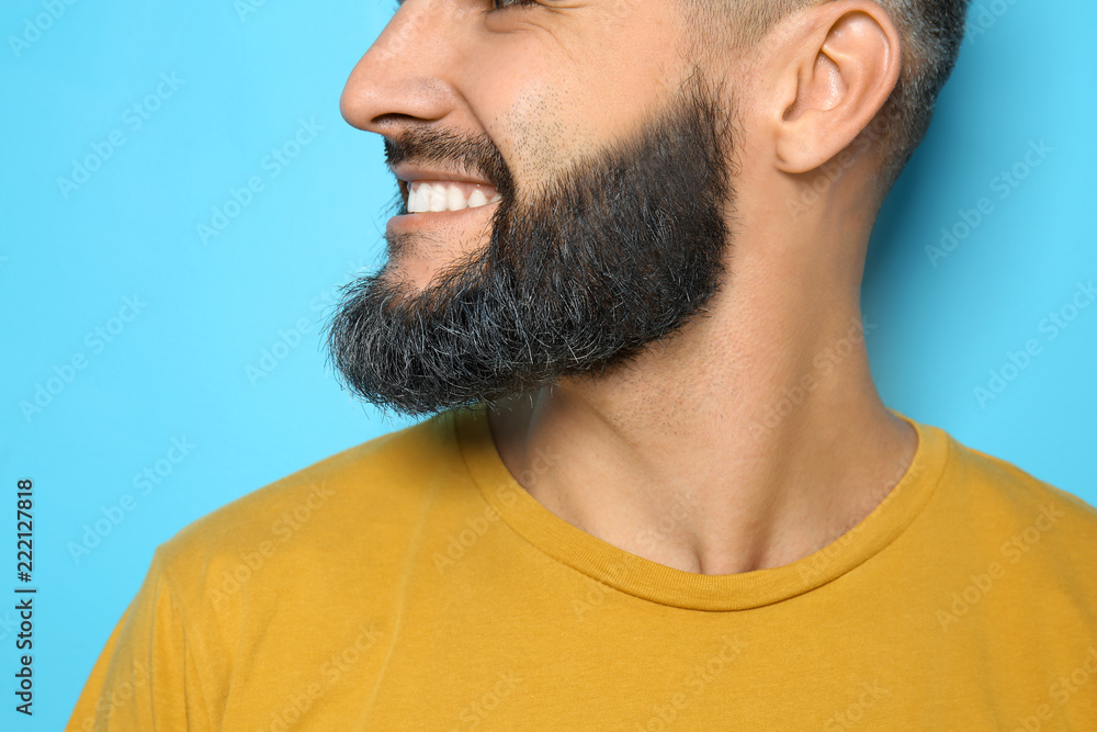 Handsome man with dyed beard on color background, closeup