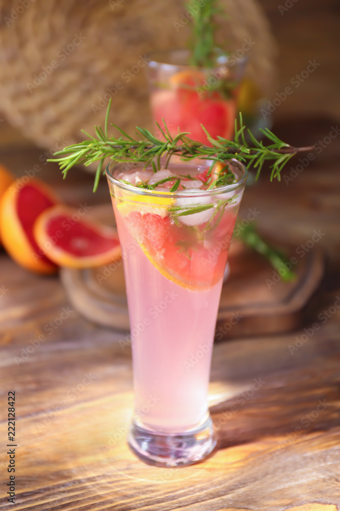 Fresh grapefruit cocktail with rosemary in glass on wooden table