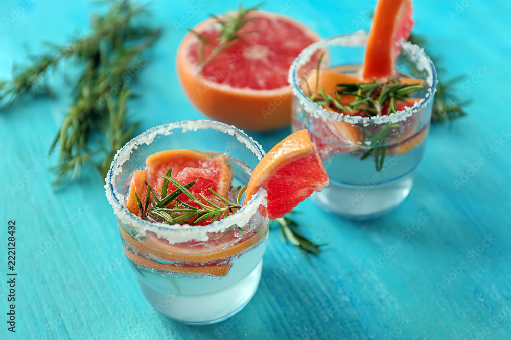 Fresh grapefruit cocktail with rosemary in glasses on color table