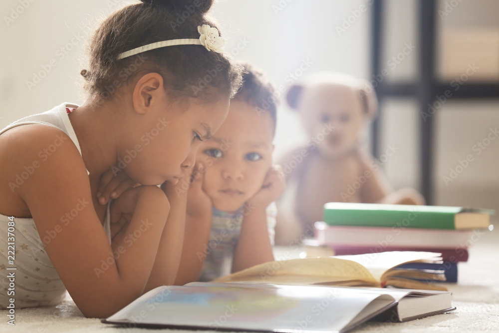 Little African-American children reading book at home