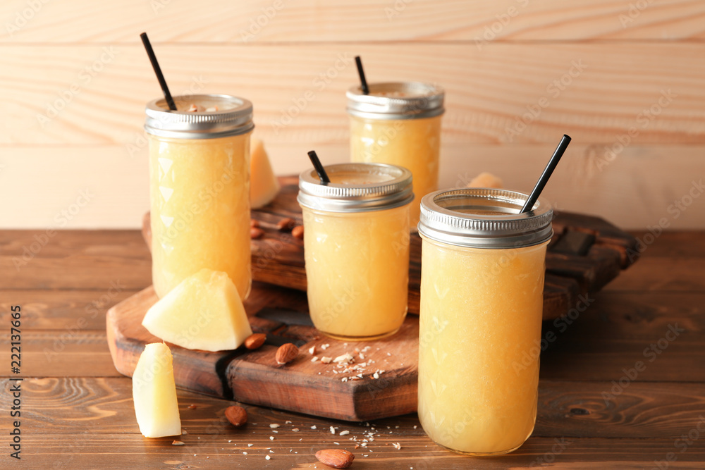 Glass jars with delicious melon smoothie on wooden table