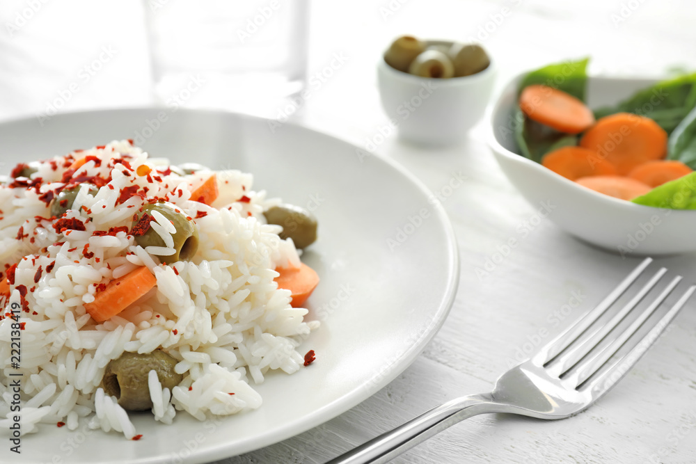 Plate with tasty boiled rice and vegetables on white wooden table, closeup