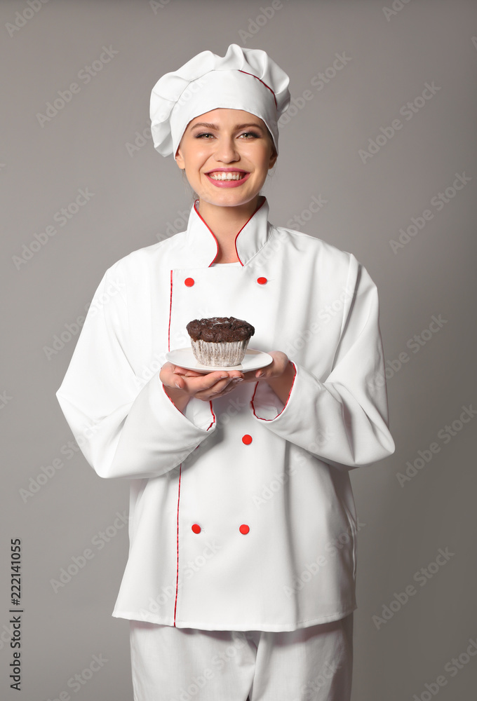 Young female chef on grey background