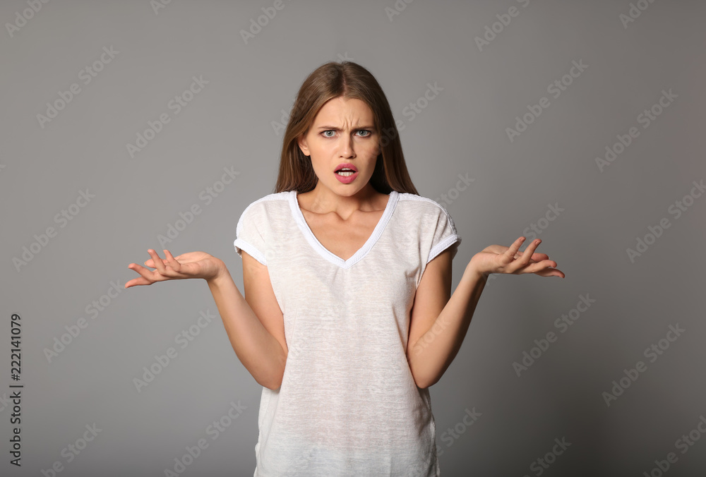 Indignant young woman on grey background