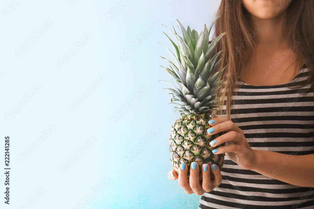 Woman with professional manicure holding delicious pineapple on light background