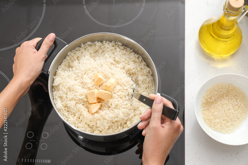 Woman cooking rice on stove in kitchen