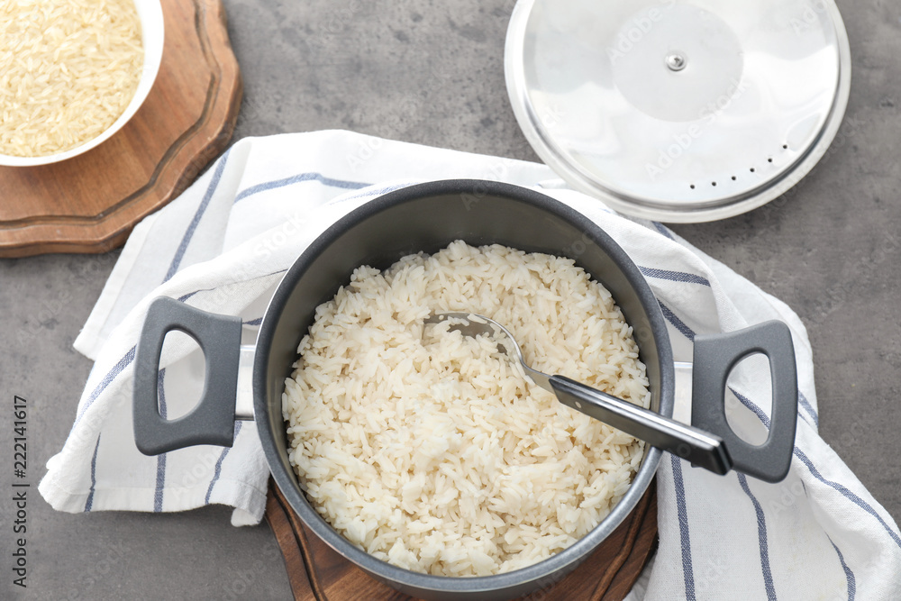 Saucepan with boiled rice on grey table