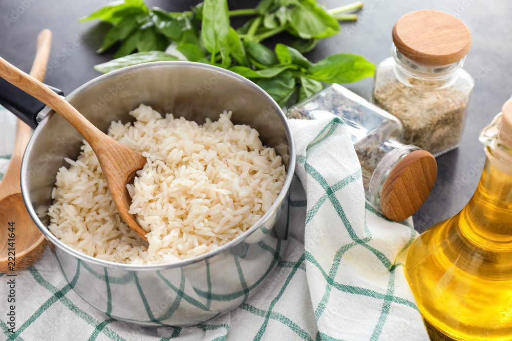 Saucepan with boiled rice on grey table