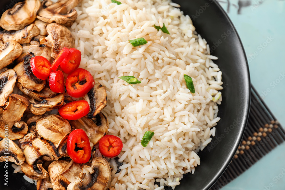 Tasty boiled rice with vegetables and mushrooms on plate, closeup