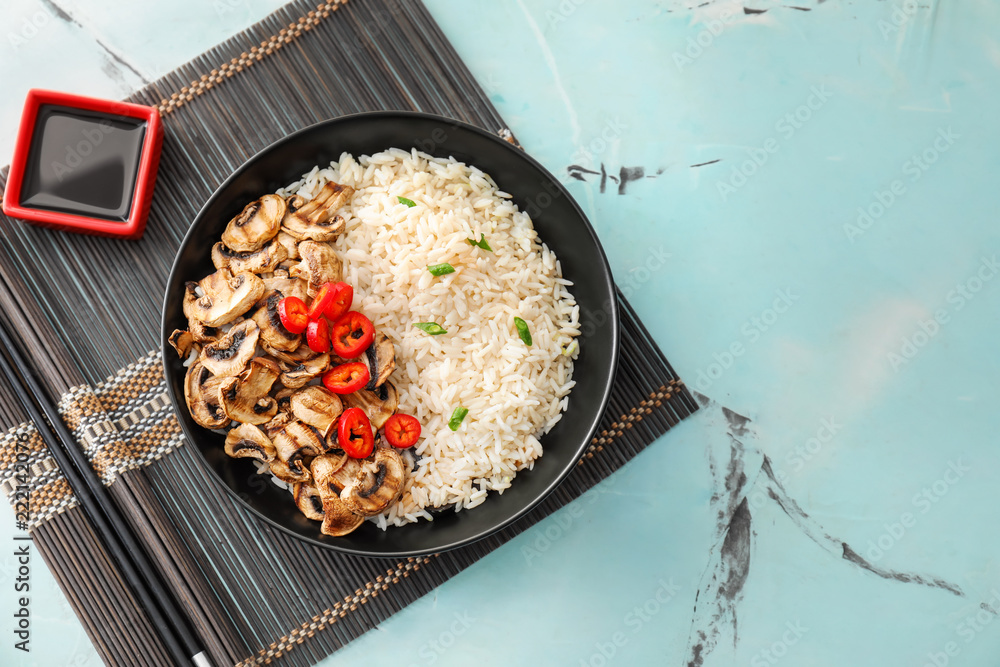 Plate with tasty boiled rice, mushrooms and vegetables on light table