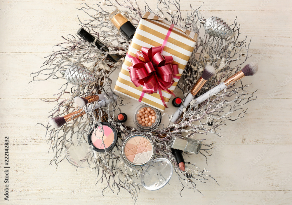 Set of decorative cosmetics with Christmas present and wreath on white wooden table