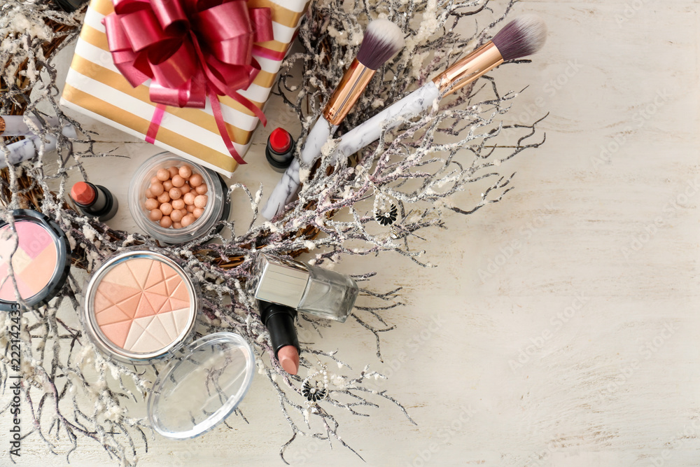 Set of decorative cosmetics with Christmas present and wreath on white wooden table