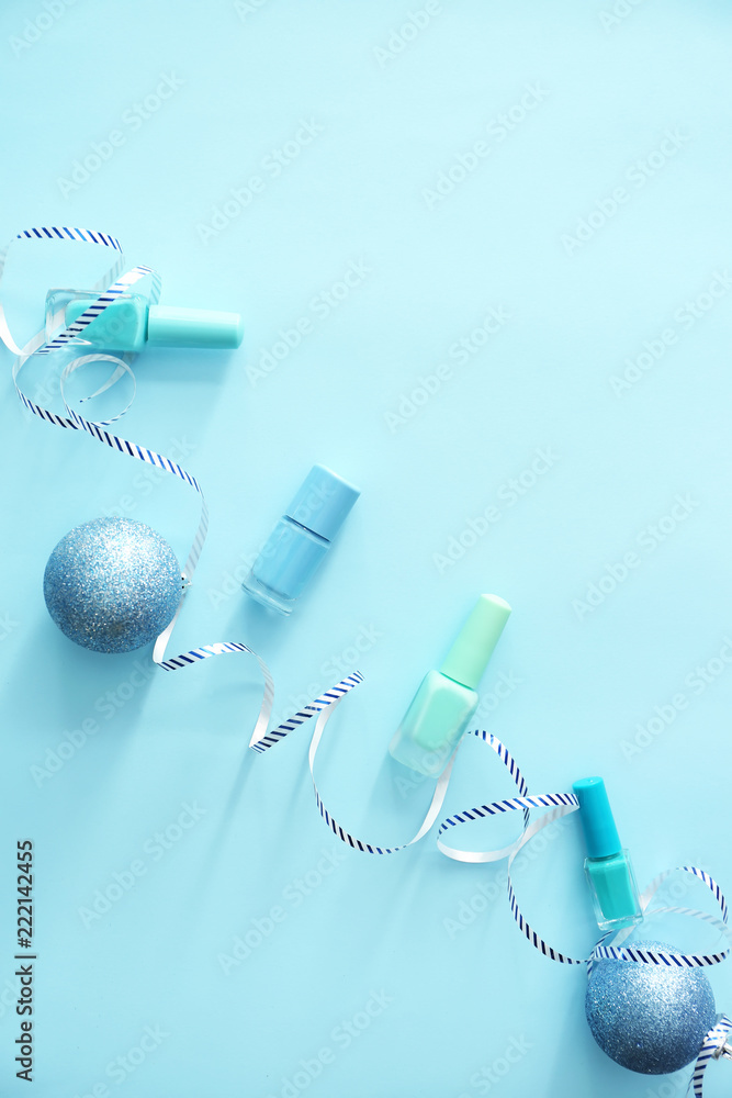 Bottles of nail polish with Christmas decorations on color background