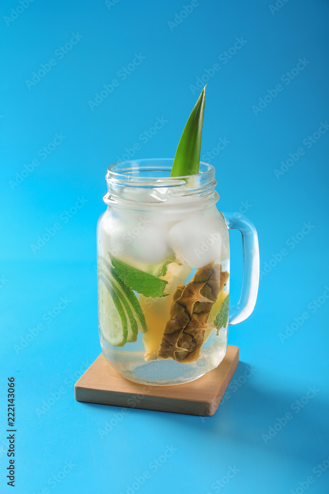 Mason jar with cold pineapple drink on blue background