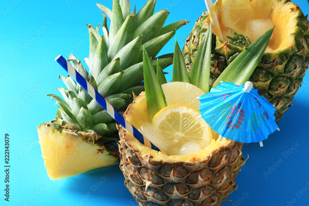 Delicious fresh cocktail with lemon in pineapples on blue background