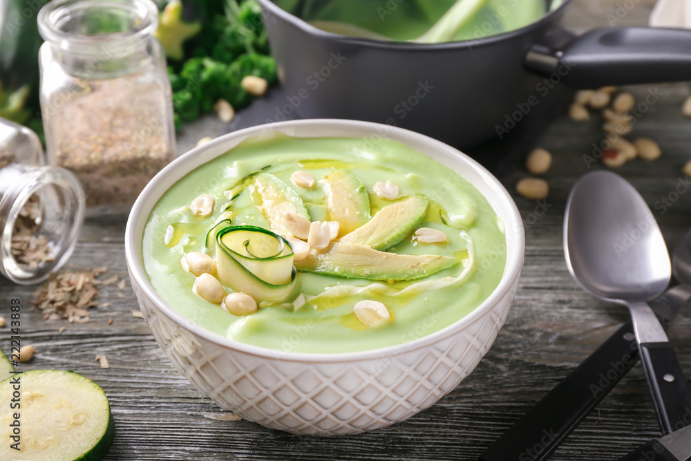 Bowl with delicious zucchini soup on wooden table