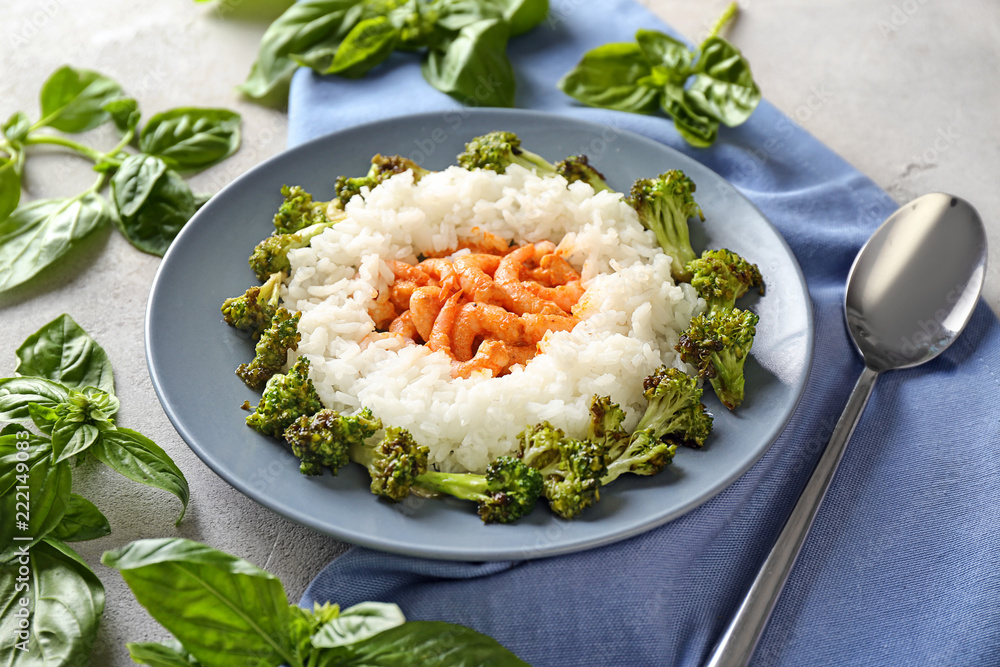 Plate with boiled rice, broccoli and shrimps on grey background