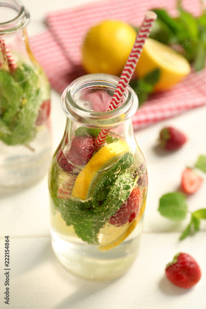 Bottle of fresh strawberry lemonade on light wooden table