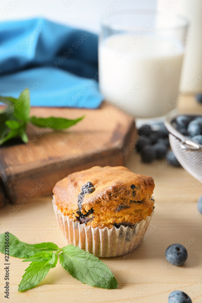 Tasty blueberry muffin on light wooden table