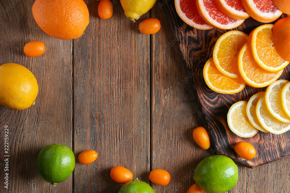 Various delicious citrus fruits with cutting board on wooden background