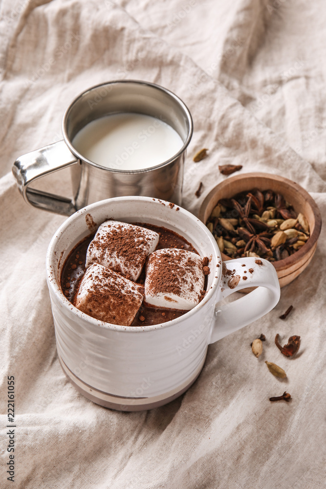 Cup of hot chocolate with marshmallows, milk and spices on napkin