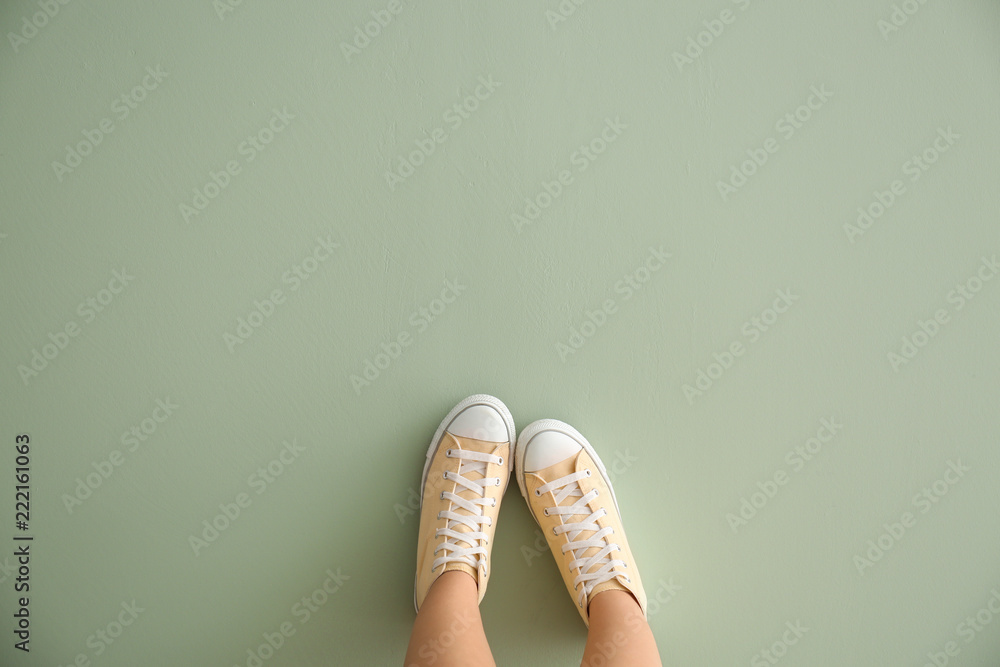 Legs of woman in casual shoes on color background