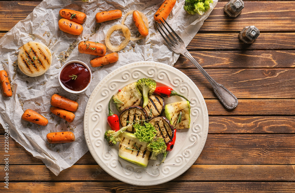 Plate with tasty grilled vegetables and tomato sauce on wooden table