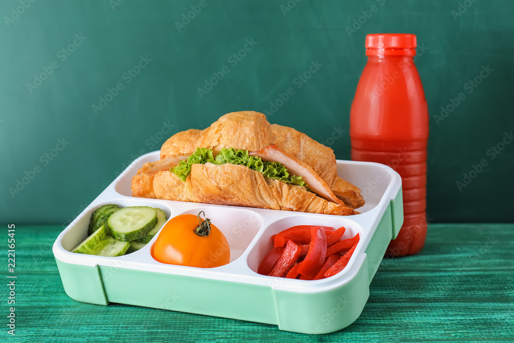 Lunch box with appetizing food on color wooden table