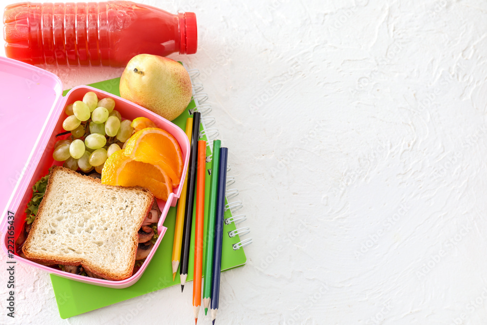 Lunch box with appetizing food and stationery on light table