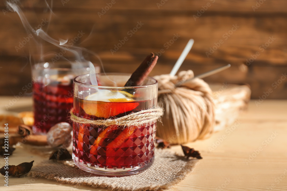 Glass of delicious hot mulled wine on wooden table