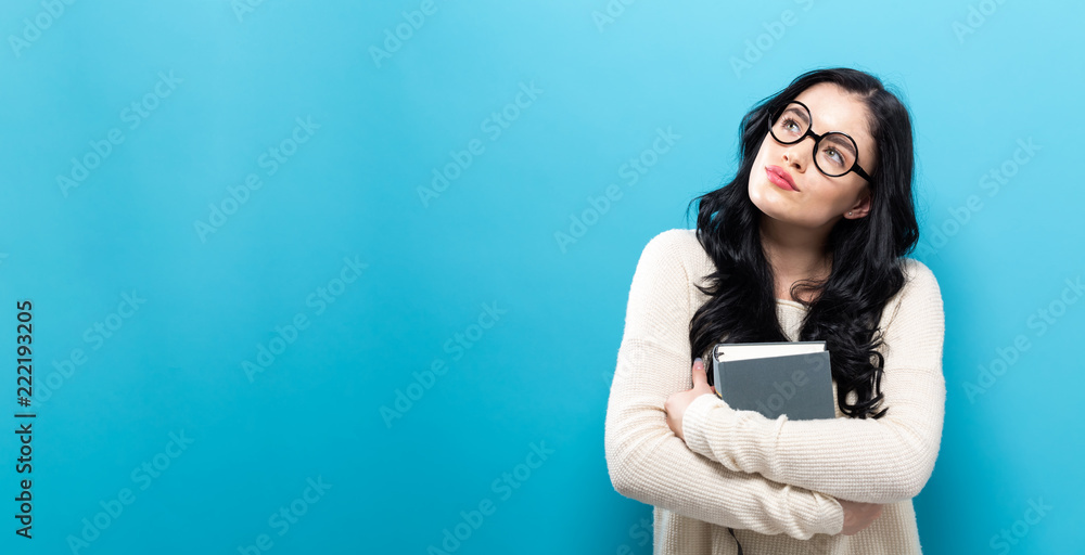 Young woman with a book on a solid background