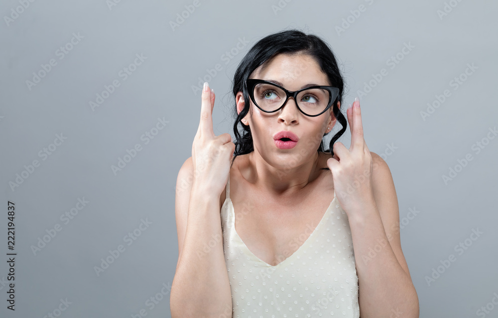 Young woman crossing her fingers and wishing for good luck