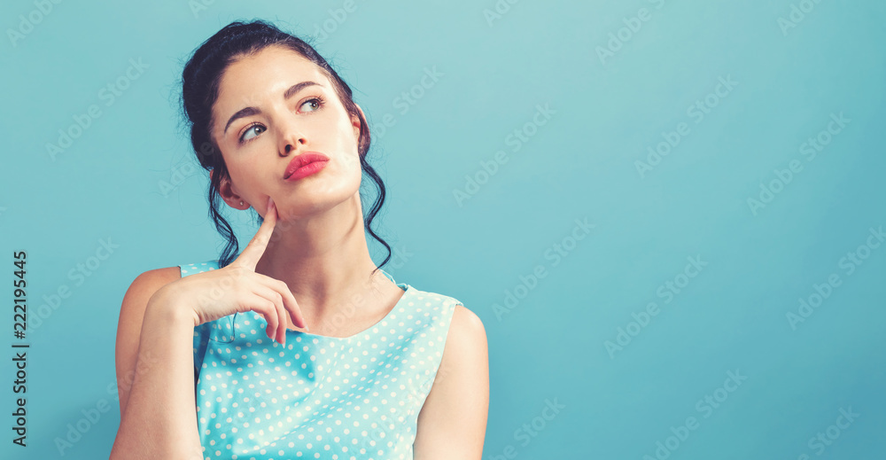 Young woman in a thoughtful pose on a solid background