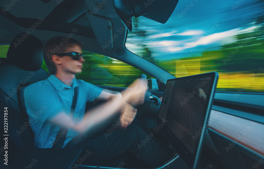 Man driving a luxury vehicle down the road with motion blur