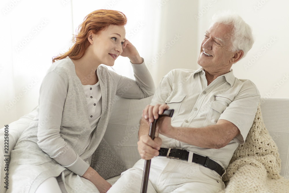 Man with a cane talking to his daughter and smiling