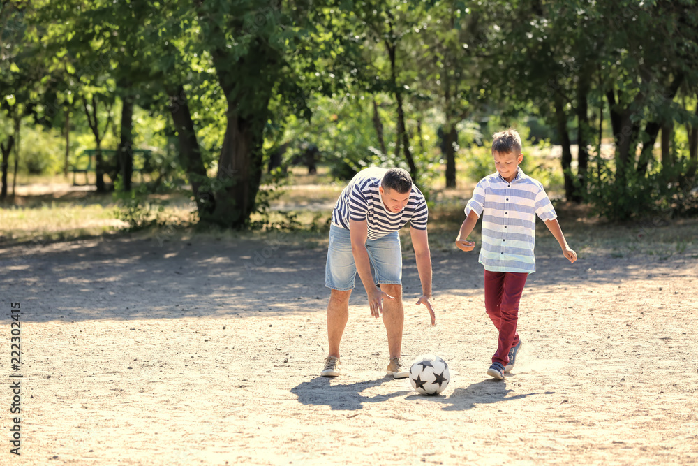 Little boy with his dad playing football outdoors