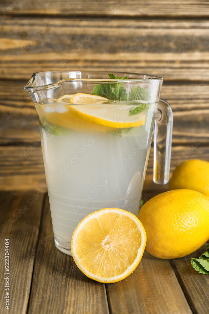 Jug of fresh lemonade on wooden table