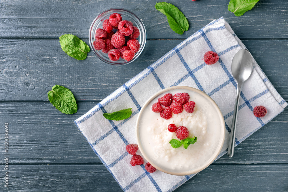 Bowls with delicious rice pudding and berries on wooden table