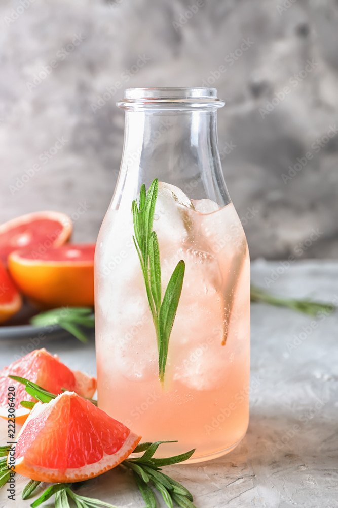 Bottle of refreshing grapefruit lemonade with rosemary on table